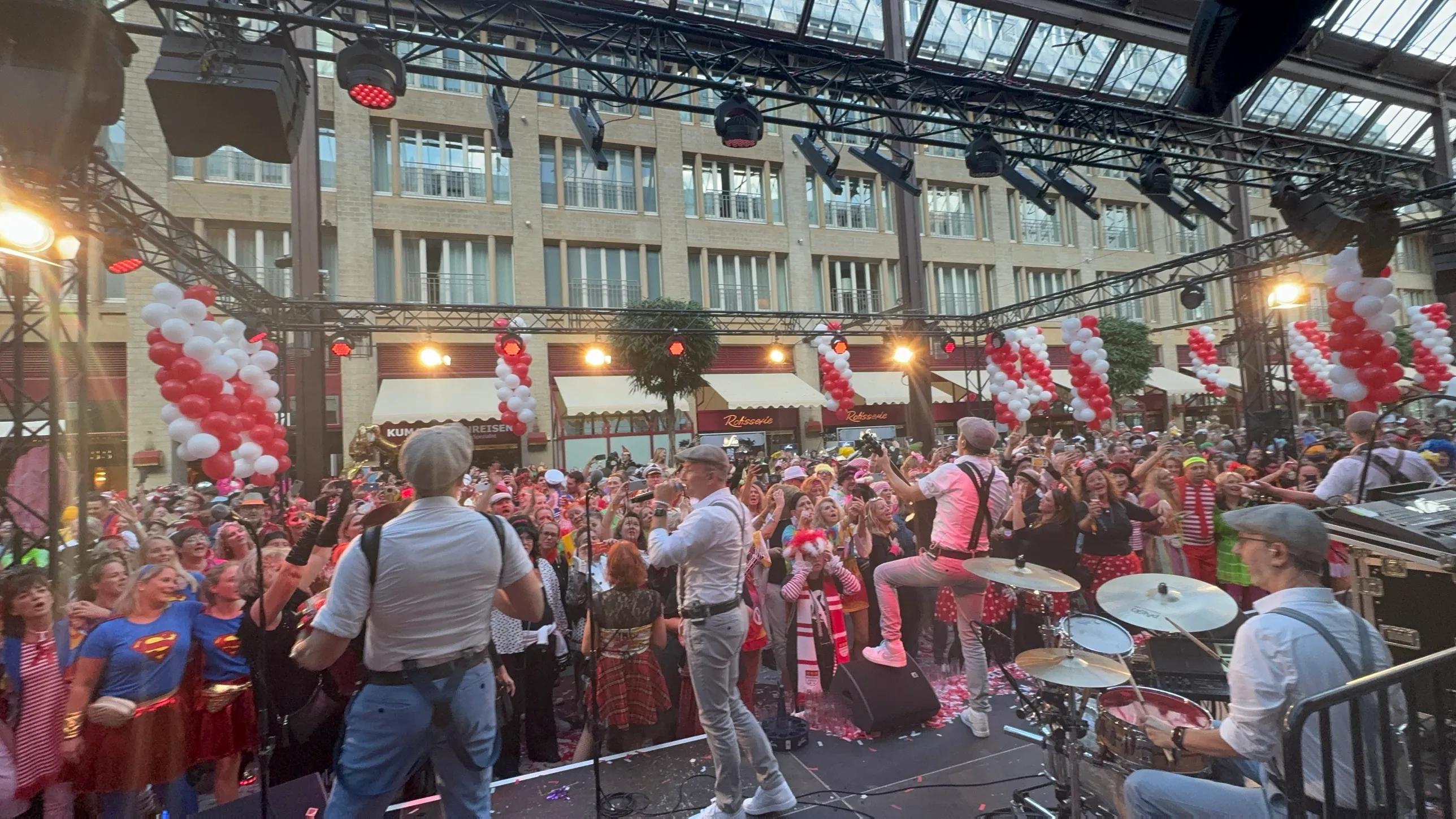 Band mit Schiebermützen und Hosenträgern auf der Bühne der Passage, davor die volle Passage im Abendlicht